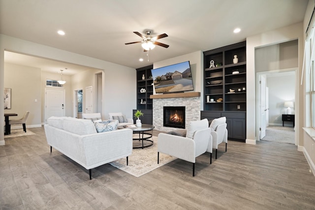 living area featuring recessed lighting, a fireplace, light wood-style flooring, and baseboards