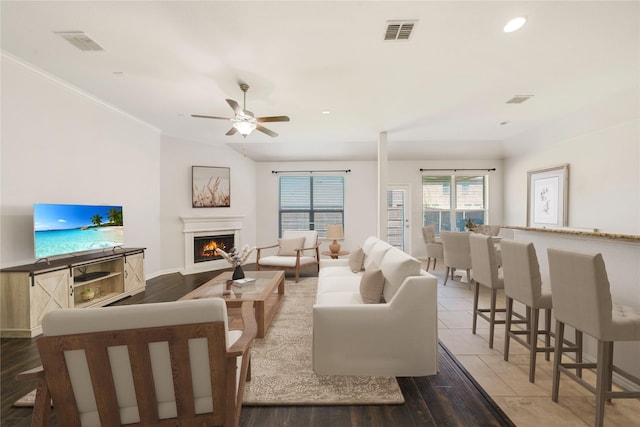 12221 Knots Ln, Frisco, TX 75036 - living room featuring visible vents, wood finished floors, ceiling fan, and a lit fireplace