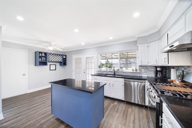 kitchen featuring stainless steel appliances, wood finished floors, a kitchen island, a sink, and ornamental molding