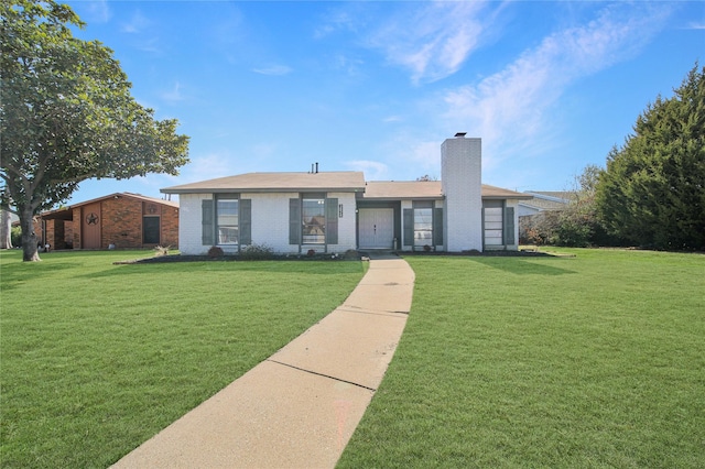 ranch-style house featuring a front lawn, a chimney, and brick siding