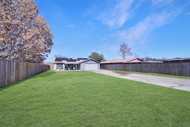 view of yard featuring fence private yard, driveway, and an attached garage