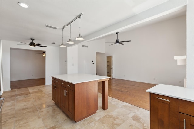 kitchen featuring open floor plan, hanging light fixtures, light countertops, and visible vents