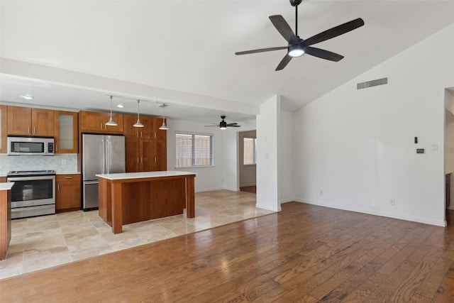 kitchen featuring visible vents, appliances with stainless steel finishes, brown cabinets, and light countertops