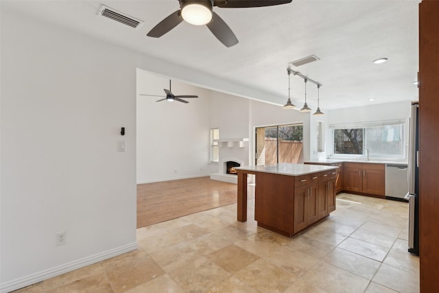 kitchen featuring visible vents, dishwasher, a lit fireplace, vaulted ceiling, and a kitchen bar