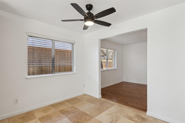 spare room with a ceiling fan and baseboards