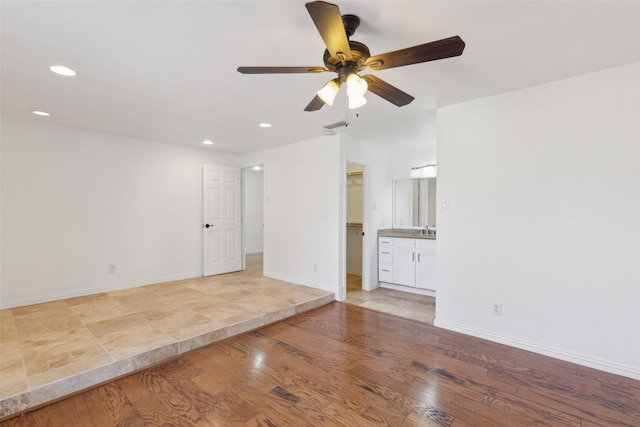 unfurnished living room with recessed lighting, a sink, light wood-style flooring, and baseboards