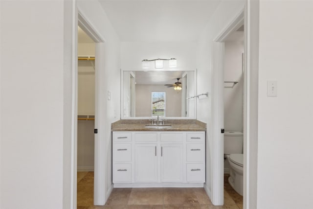 full bathroom with a ceiling fan, a walk in closet, vanity, and toilet