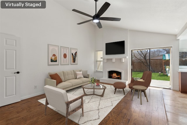 living area with a warm lit fireplace, a healthy amount of sunlight, and hardwood / wood-style flooring