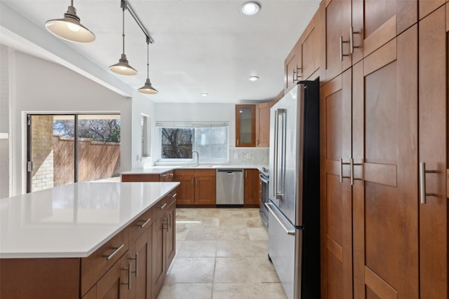 kitchen featuring plenty of natural light, appliances with stainless steel finishes, brown cabinets, and decorative backsplash