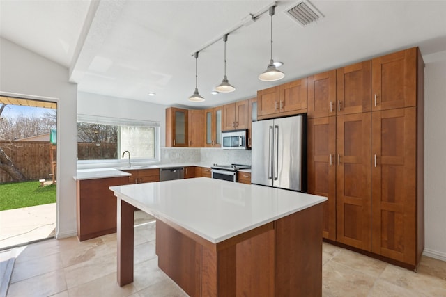 kitchen featuring stainless steel appliances, a sink, visible vents, brown cabinetry, and glass insert cabinets