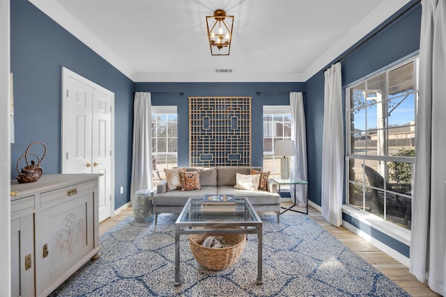 living area featuring light wood-type flooring, visible vents, crown molding, and baseboards