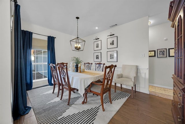 dining space with a notable chandelier, wood finished floors, visible vents, and baseboards