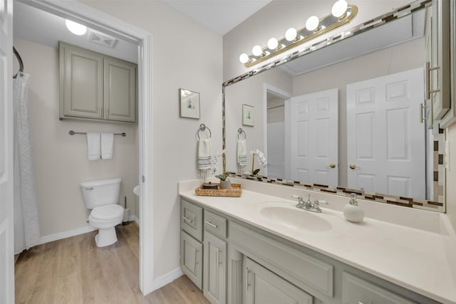 bathroom featuring visible vents, toilet, vanity, wood finished floors, and baseboards