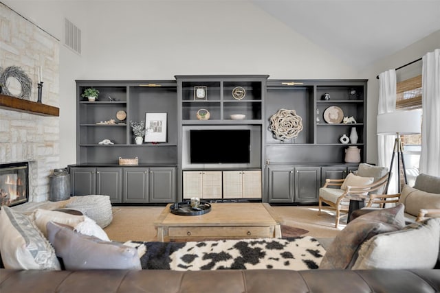 living room featuring high vaulted ceiling, visible vents, and a stone fireplace