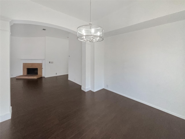 interior space with a brick fireplace, baseboards, and dark wood finished floors