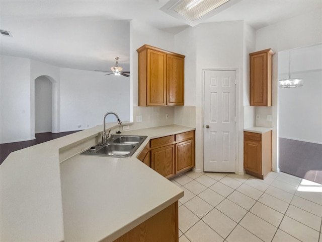 kitchen featuring a peninsula, light tile patterned floors, light countertops, and a sink