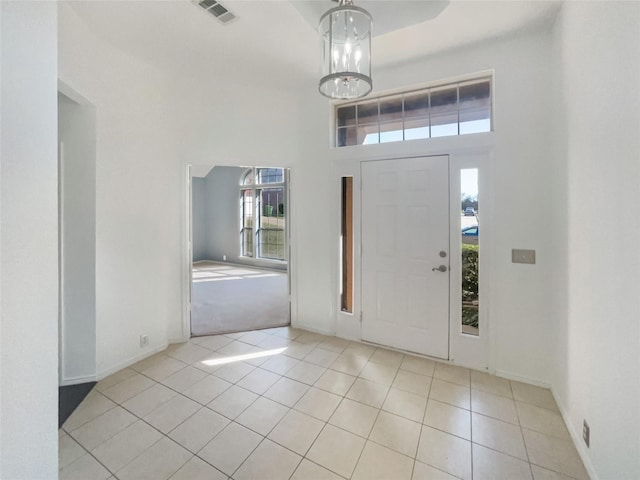 entryway with tile patterned flooring, visible vents, a towering ceiling, and baseboards