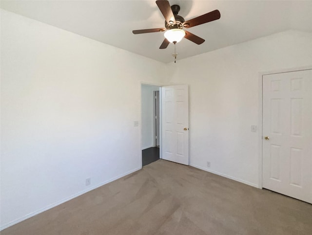 spare room featuring light colored carpet, ceiling fan, and baseboards