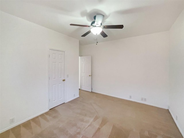 spare room with ceiling fan, baseboards, and light colored carpet