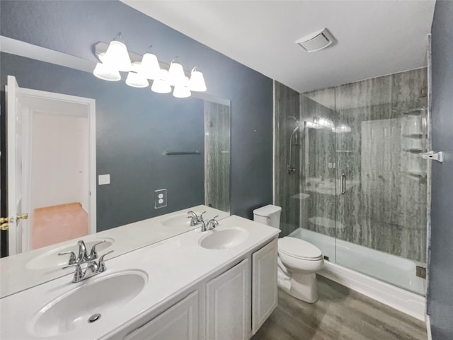 bathroom featuring toilet, a stall shower, a sink, and wood finished floors