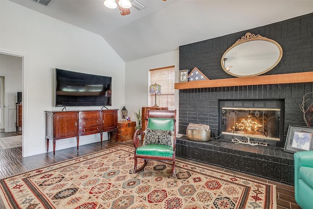 living area with a fireplace, a ceiling fan, vaulted ceiling, and wood finished floors