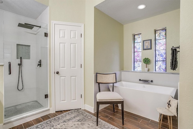 bathroom with a freestanding bath, a stall shower, baseboards, and wood tiled floor