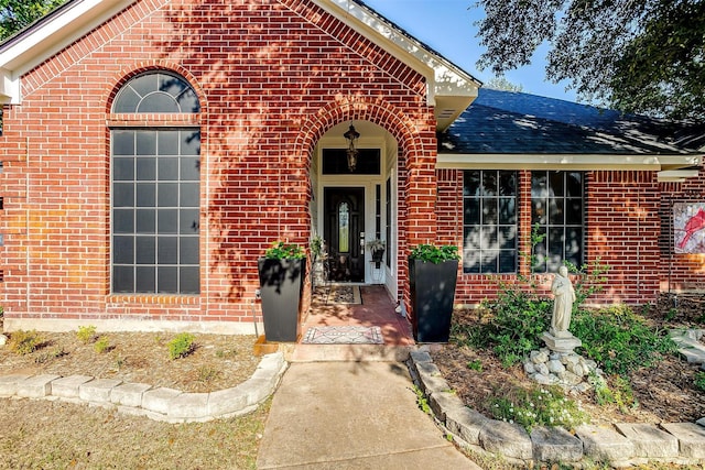 property entrance featuring brick siding and roof with shingles