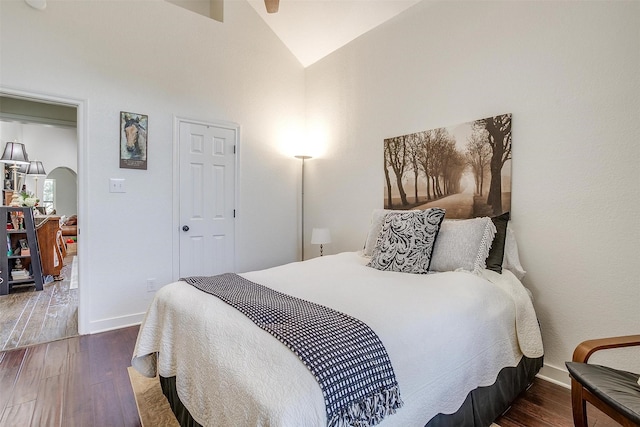 bedroom featuring baseboards, arched walkways, and wood finished floors