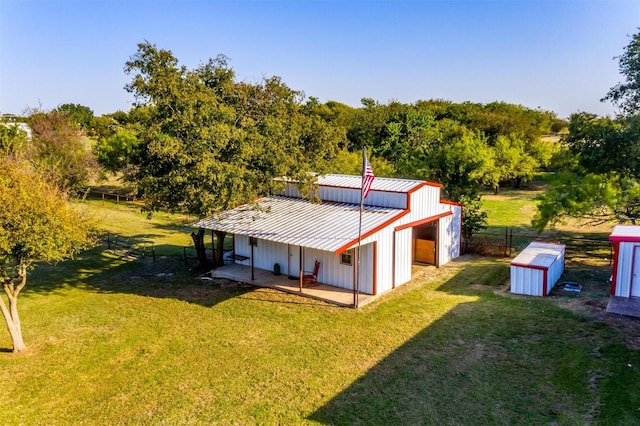 back of house featuring a lawn, an outdoor structure, and fence