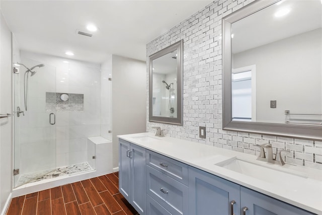 full bath featuring a stall shower, tasteful backsplash, a sink, and wood finish floors