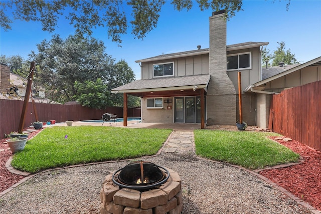 rear view of property with a yard, board and batten siding, a fenced backyard, and a fenced in pool