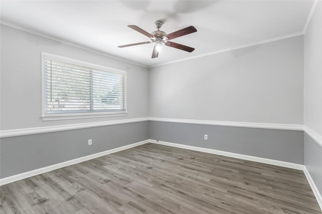 empty room featuring a ceiling fan, crown molding, baseboards, and wood finished floors