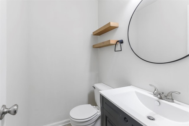 bathroom featuring toilet, baseboards, and vanity