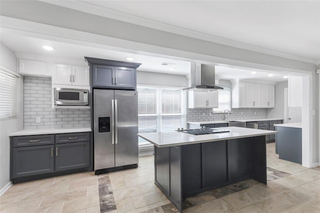 kitchen with stainless steel appliances, a sink, light countertops, wall chimney exhaust hood, and crown molding