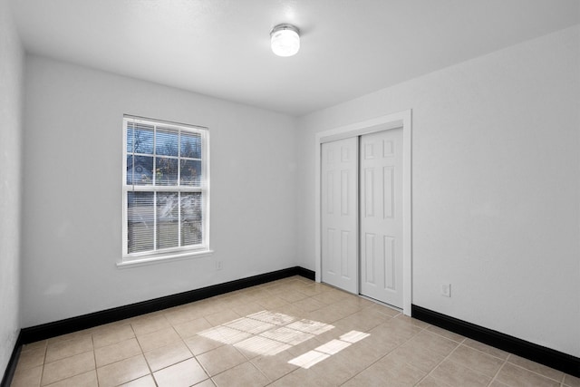 unfurnished bedroom with baseboards, a closet, and light tile patterned flooring