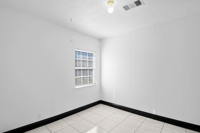 spare room featuring baseboards, visible vents, a textured ceiling, and light tile patterned flooring