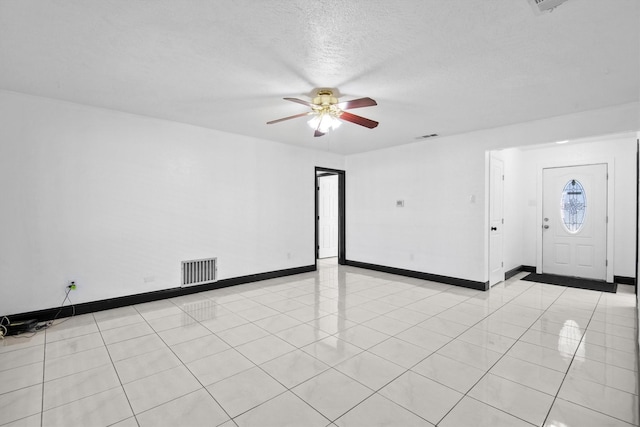 interior space with a textured ceiling, ceiling fan, visible vents, and baseboards