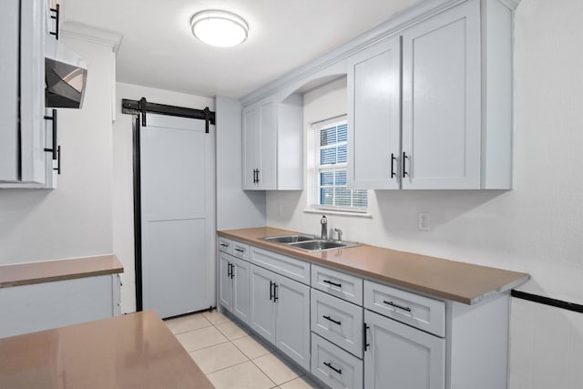 kitchen with white cabinets, light tile patterned floors, a sink, and a barn door