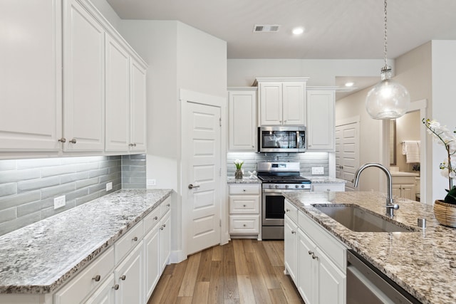3830 Dalea Dr, Prosper, TX 75078 - kitchen featuring light wood finished floors, visible vents, appliances with stainless steel finishes, white cabinetry, and a sink