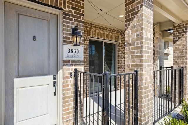 entrance to property with brick siding and fence