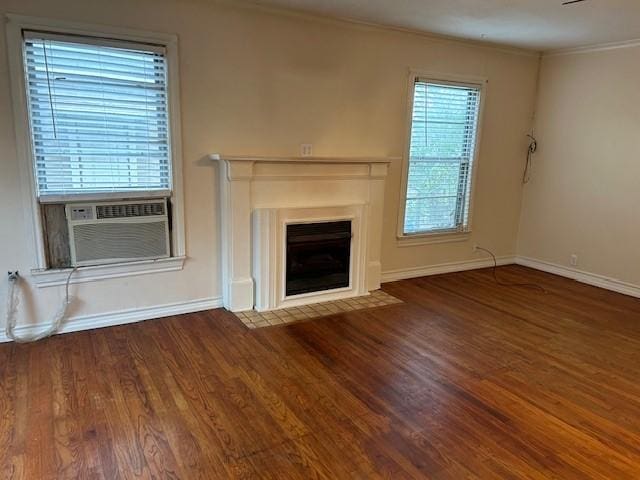 unfurnished living room with baseboards, a fireplace with flush hearth, wood finished floors, crown molding, and cooling unit