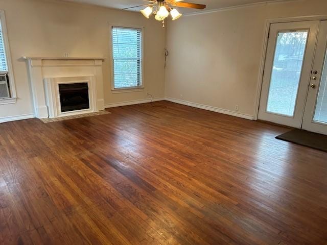 unfurnished living room with a fireplace with flush hearth, ceiling fan, baseboards, and wood finished floors