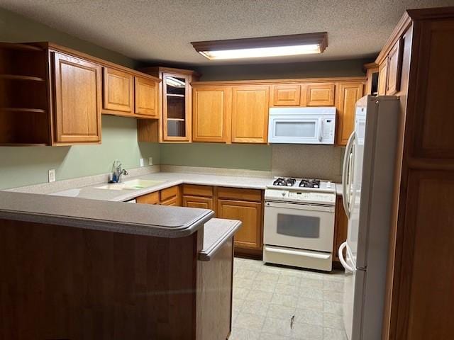 kitchen featuring white appliances, a peninsula, a textured ceiling, light floors, and a sink