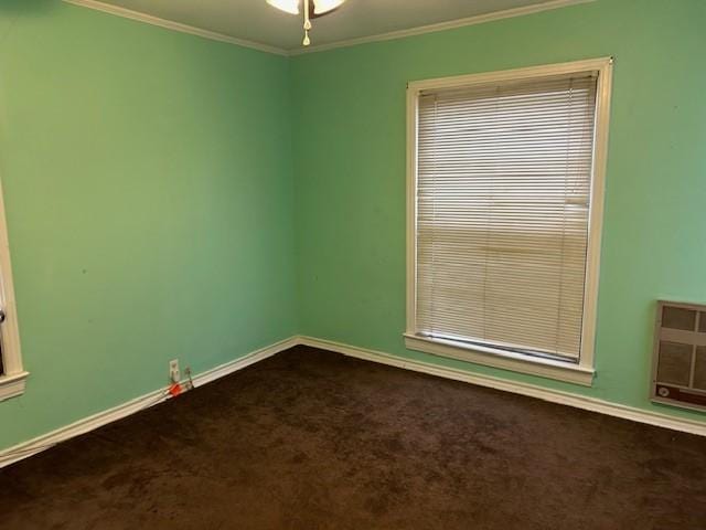 empty room with baseboards, dark carpet, and crown molding