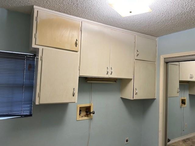 laundry area with cabinet space, hookup for a washing machine, and a textured ceiling