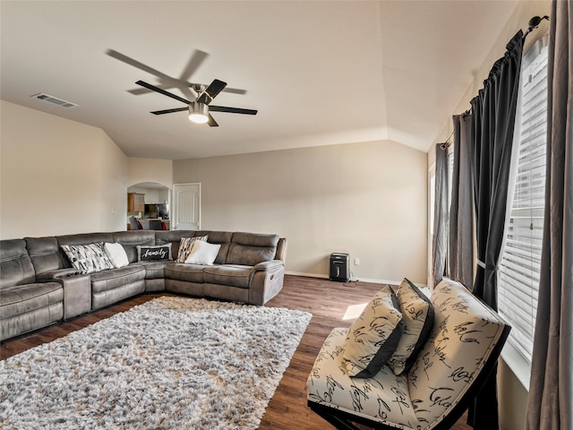 living room with arched walkways, dark wood finished floors, lofted ceiling, visible vents, and a ceiling fan