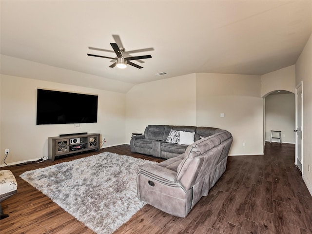 living area with a ceiling fan, arched walkways, dark wood-style flooring, and vaulted ceiling