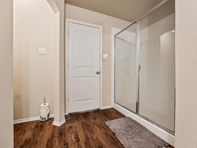 full bath featuring a stall shower, baseboards, and wood finished floors