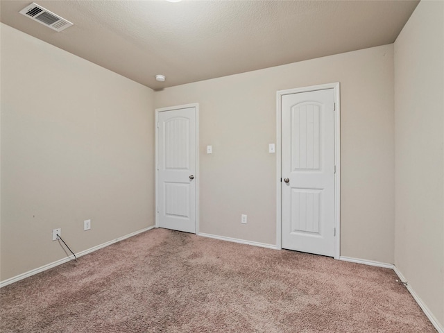 spare room with carpet, visible vents, and baseboards