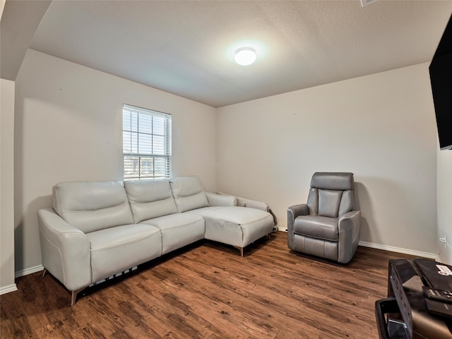 living room featuring dark wood-type flooring, a textured ceiling, and baseboards